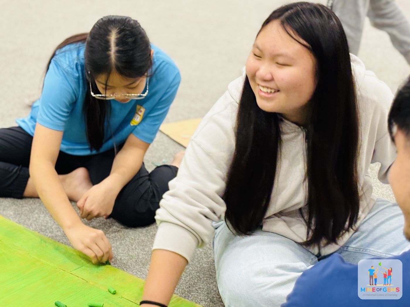 Two youths working on a craft project on the floor