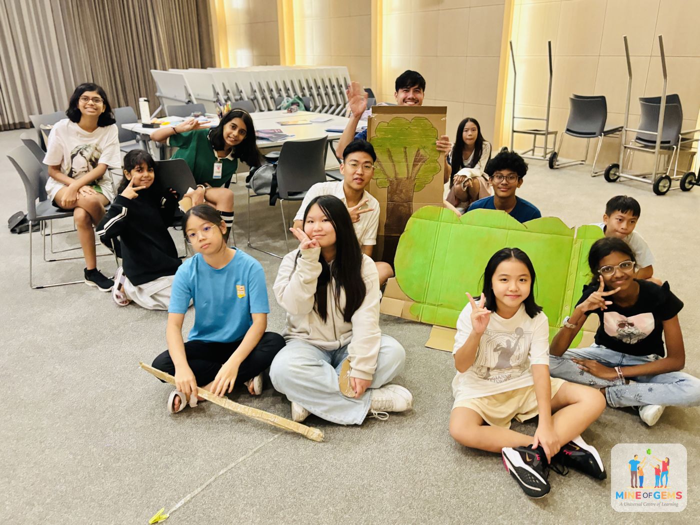 Junior youths sitting together with a cardboard tree they made