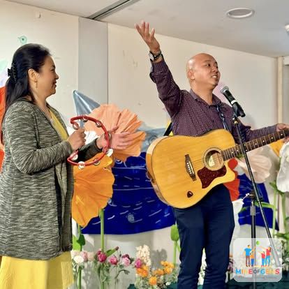 Greg singing with a guitar at a community event