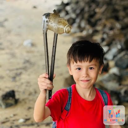 A boy holding up a plastic bottle he picked up during a clean-up