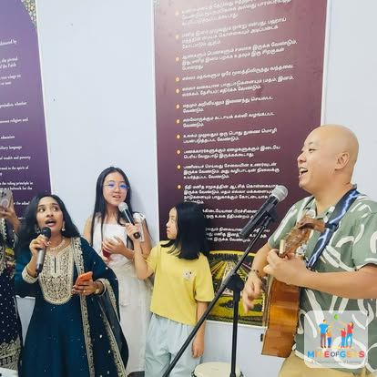Children speaking on a microphone while Greg plays guitar